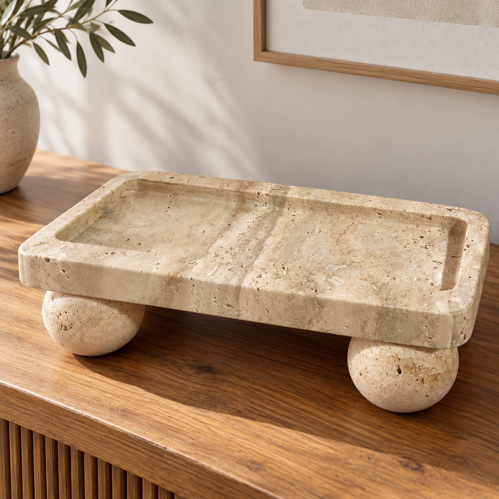 Beige travertine tray with round stone feet on a wooden console