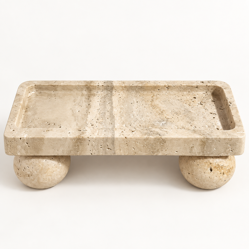 Rectangular beige travertine tray with spherical feet in a studio setting
