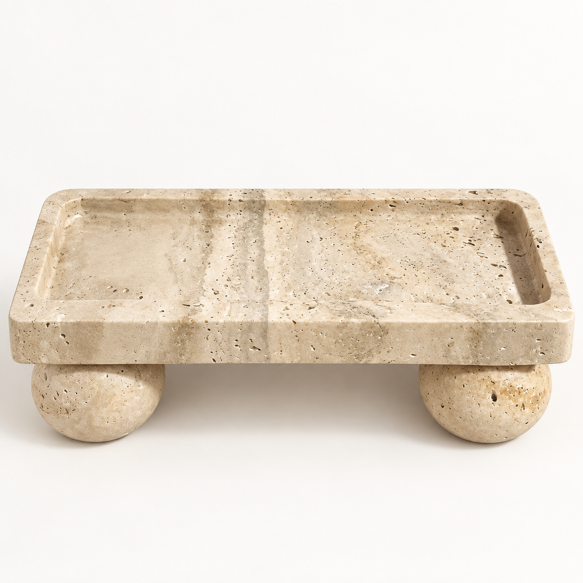 Rectangular beige travertine tray with spherical feet in a studio setting