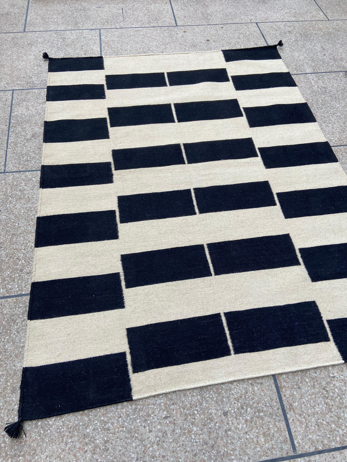 Black and ivory geometric wool kilim rug shown at an angle