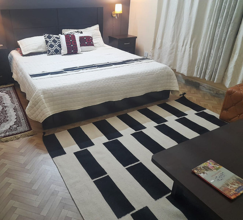 Black and ivory geometric kilim rug styled in a modern bedroom