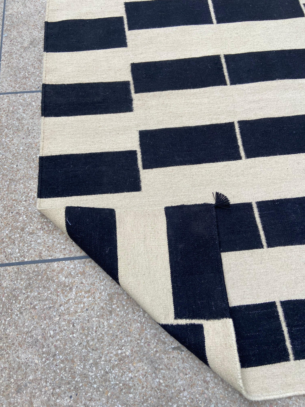 Close-up of reversible flatweave and corner tassel on black and ivory kilim rug