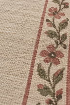Close-up of handwoven wool texture and floral vine detail