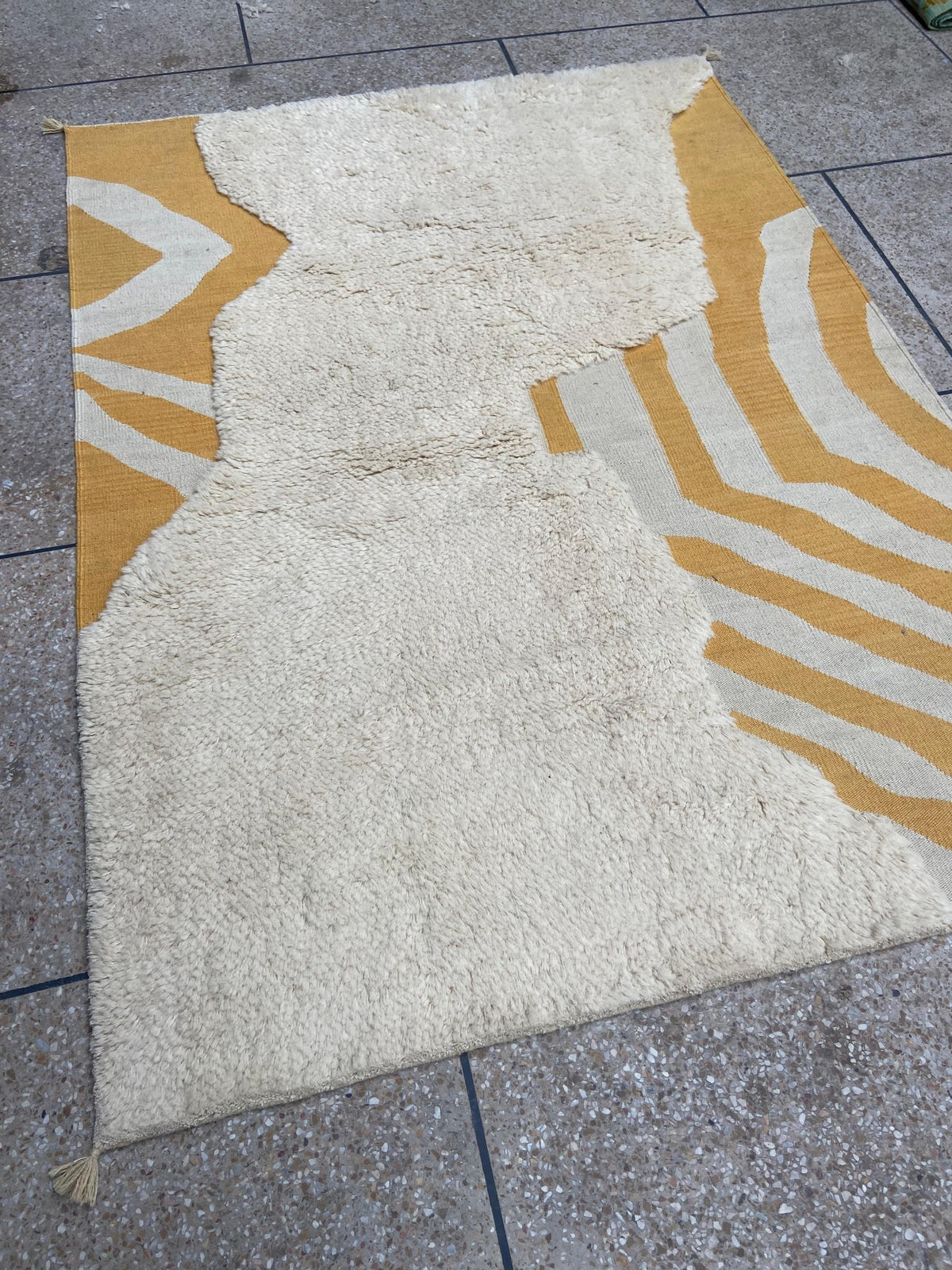 Ivory and mustard abstract Moroccan wool rug shown at an angle
