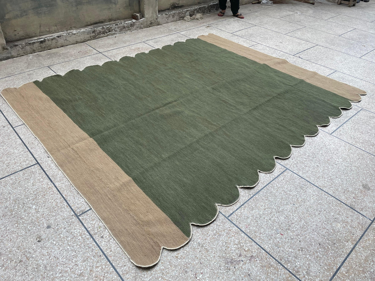 Angled full view of olive green and beige scalloped wool rug